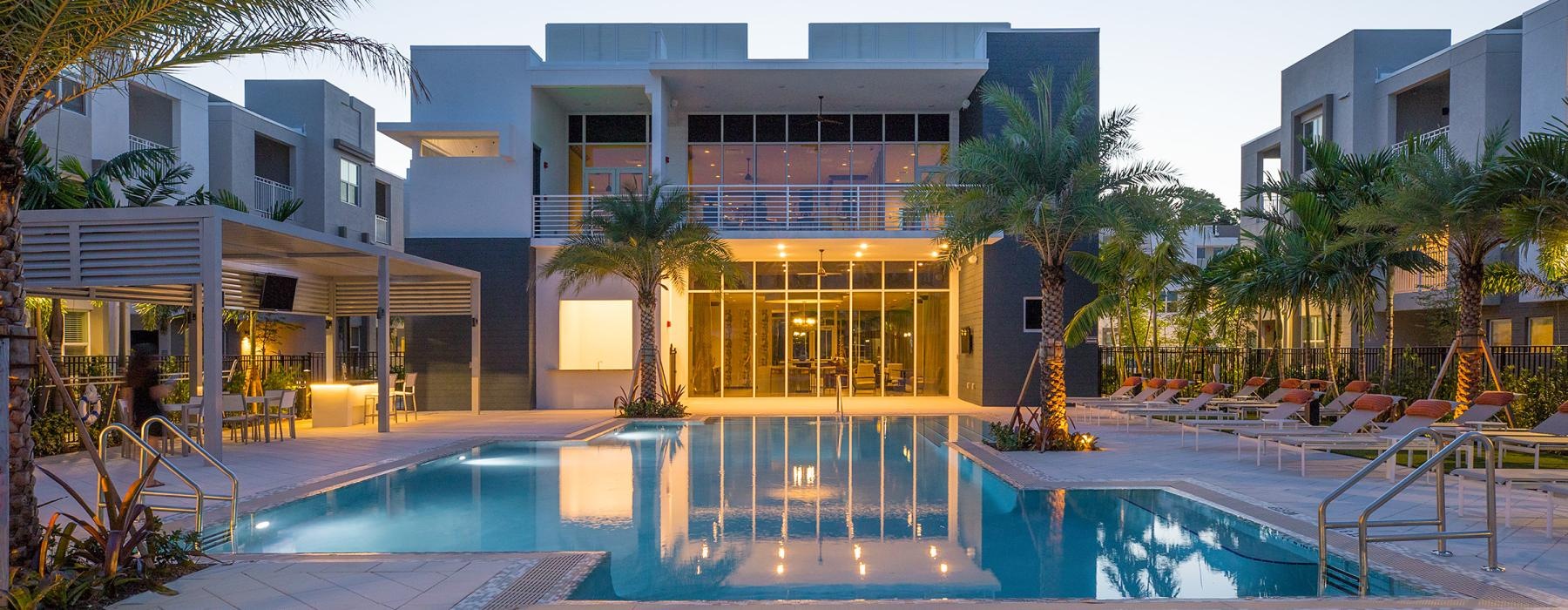 a pool in front of a building with palm trees