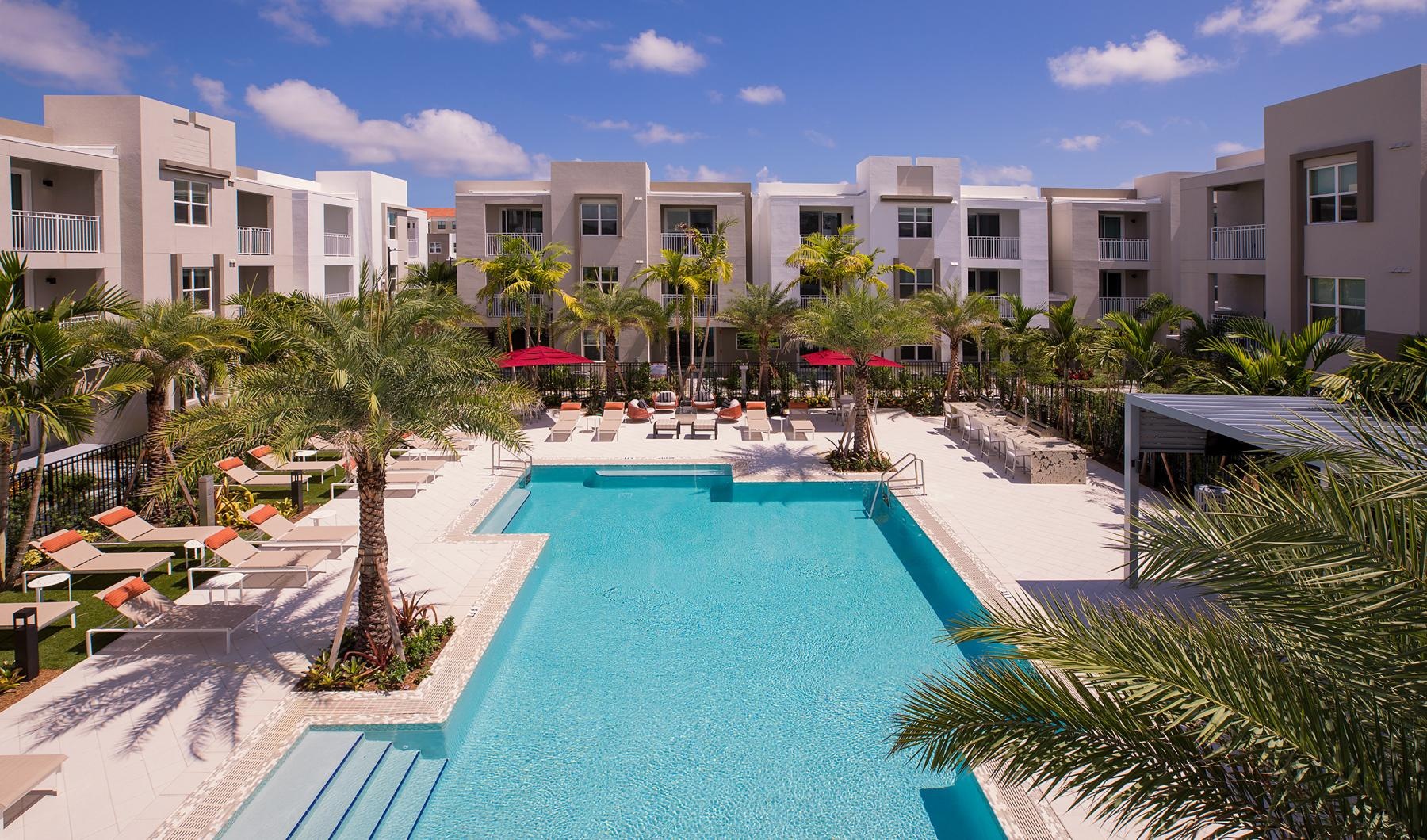 a pool in front of a building with palm trees