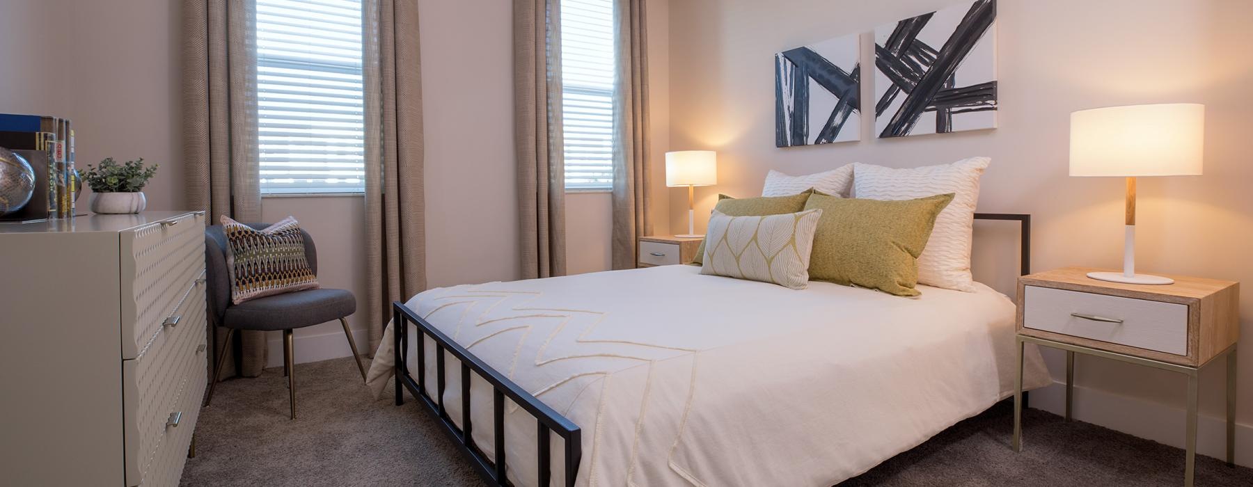 a bedroom with a bed and a side table and windows